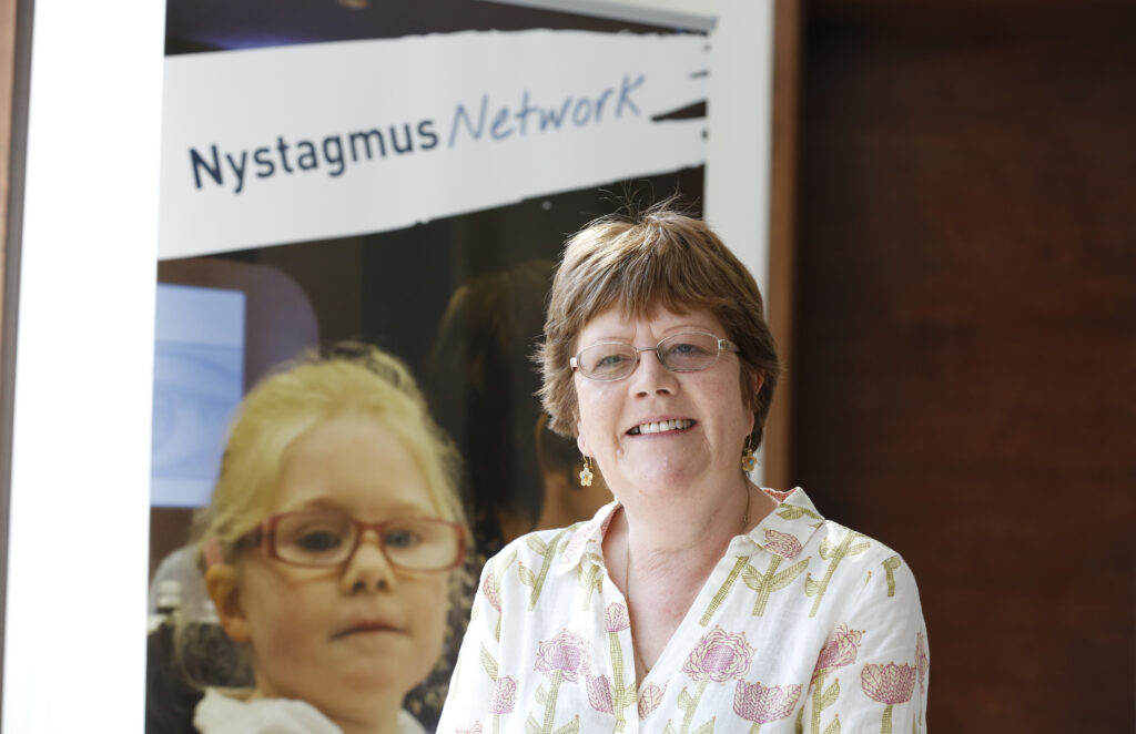 Vivien stands in front of a Nystagmus Network banner.