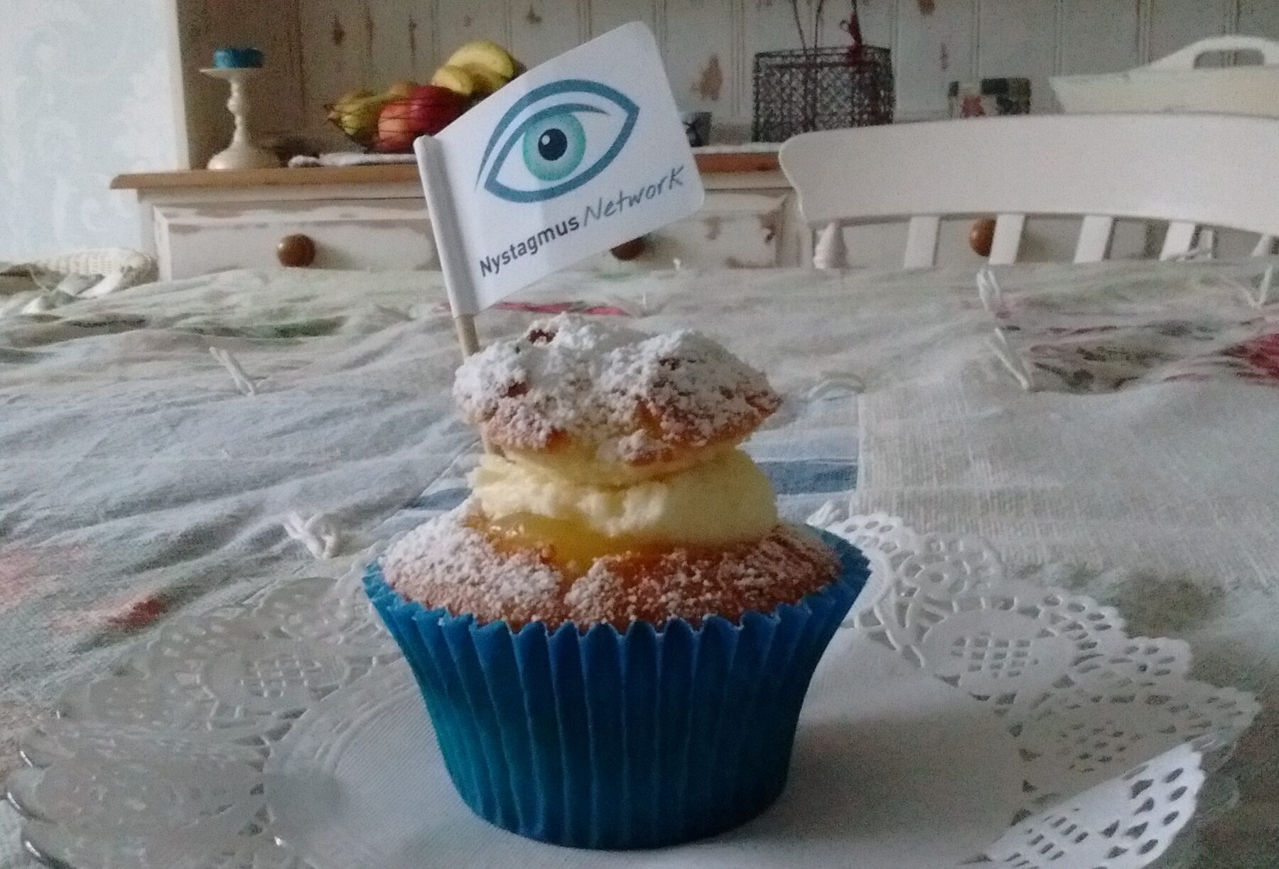 A cup cake with a paper flag bearing the Nystagmus Network logo.