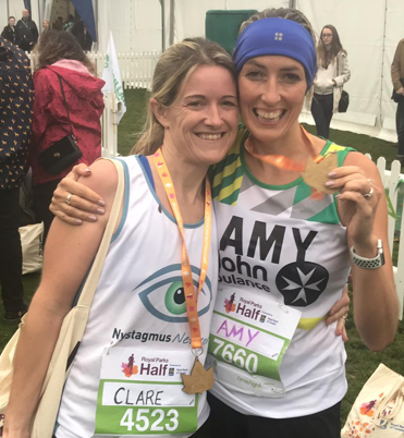 2 runners wearing Nystagmus Network show their medals after comleting the Royal Parks Half Marathon