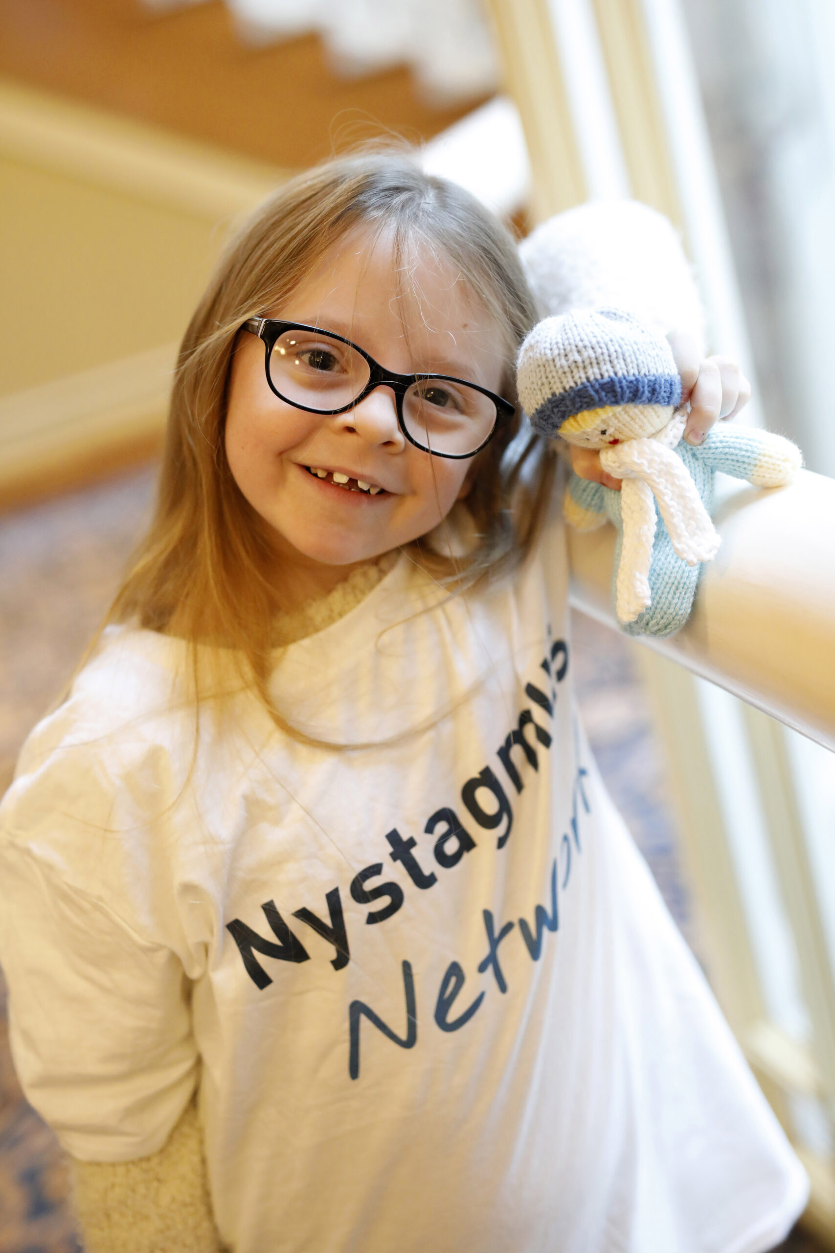 Child wearing a Nystagmus Network T shirt and holding a mascot.