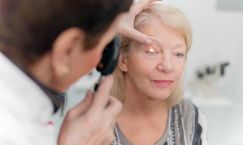 Shining a light in a woman's eye during an eye exam.