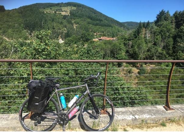 Sam's bike is leaning against railings in a mountainous landscape.