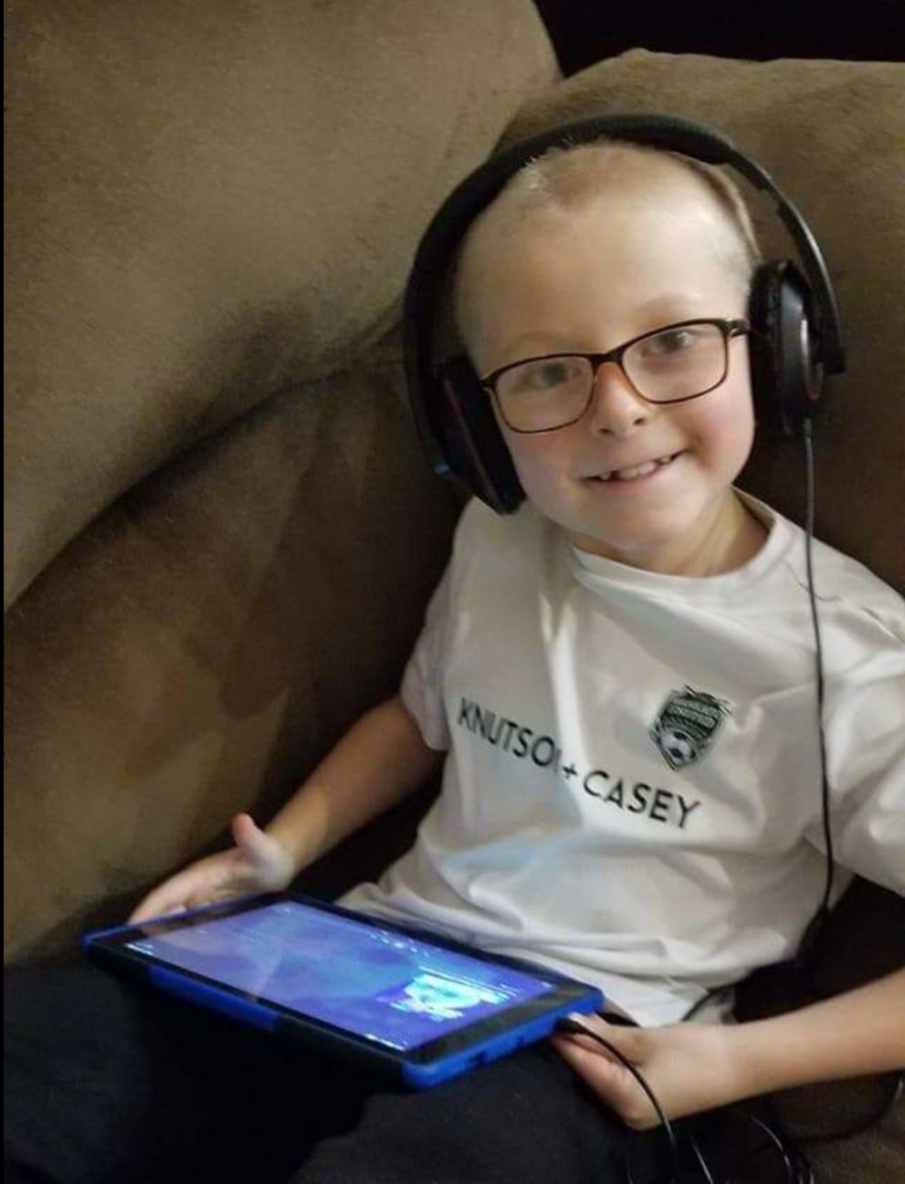 Wyatt smiles for the camera. He is wearing headphones and holding a games console.