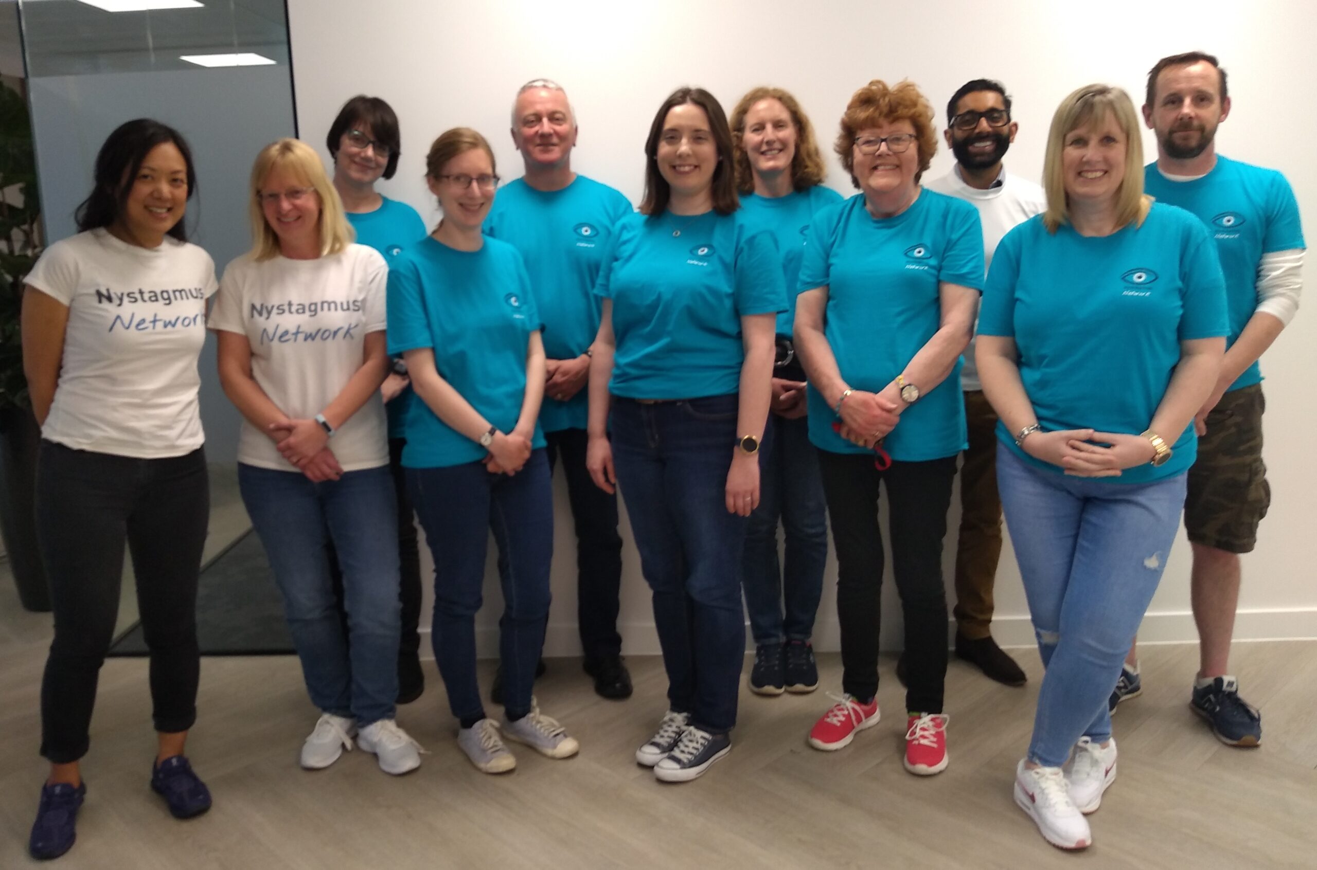 The Nystagmus Network trsutees and staff smile at the camera. They are wearing their charity T-shirts.