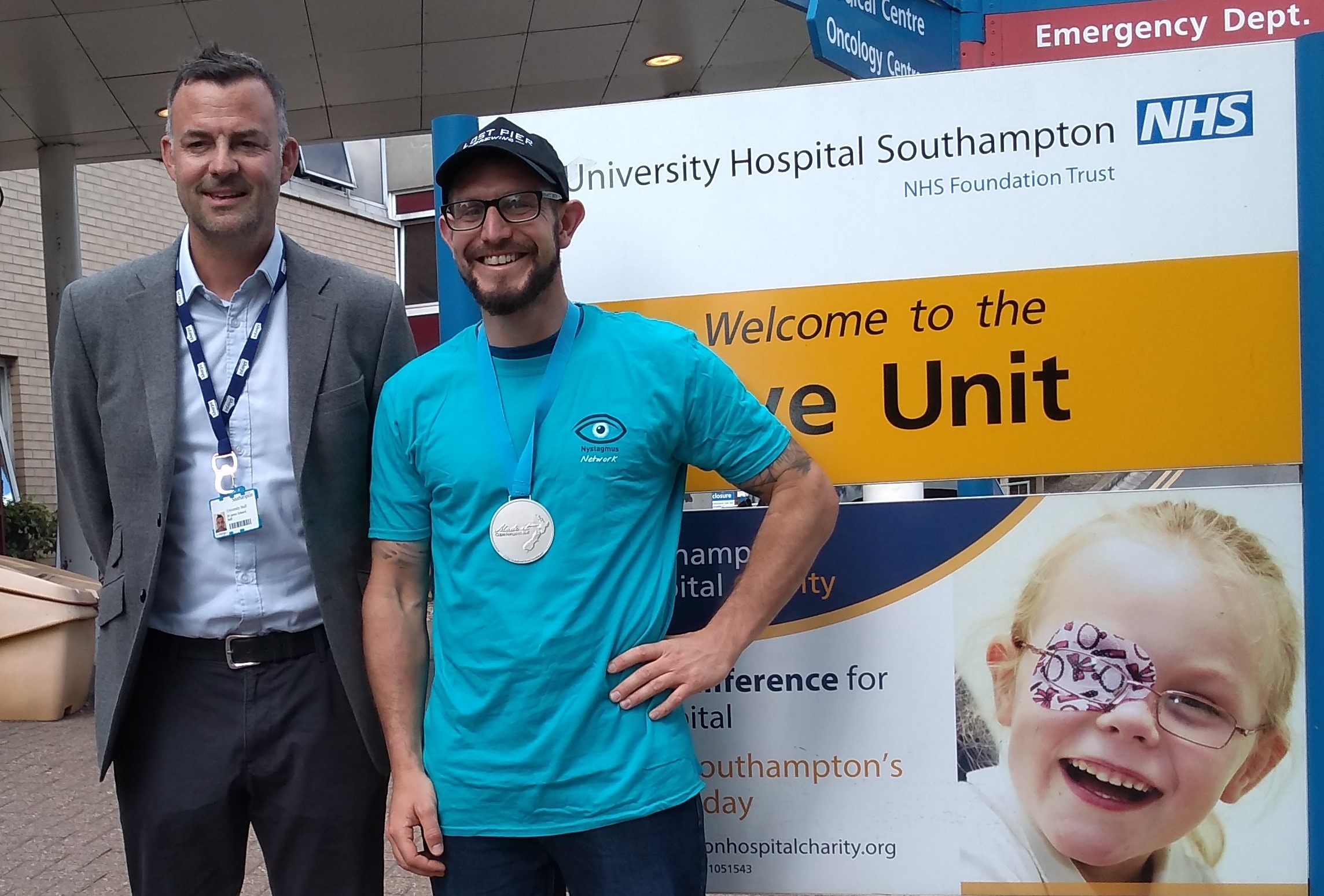 Jay Self and Mike Larcombe at University Hospital Southampton. Mike wears a Nystagmus Network T-shirt and his Te Araroa medal.