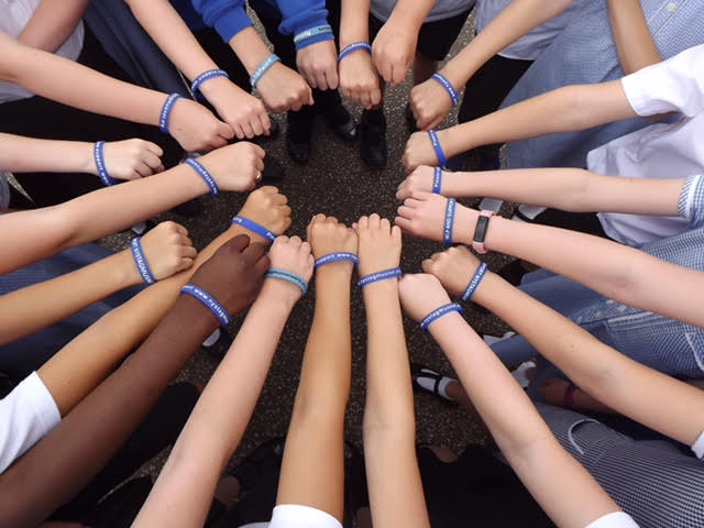 A wheel of arms all wearing Nystagmus Network wristbands.