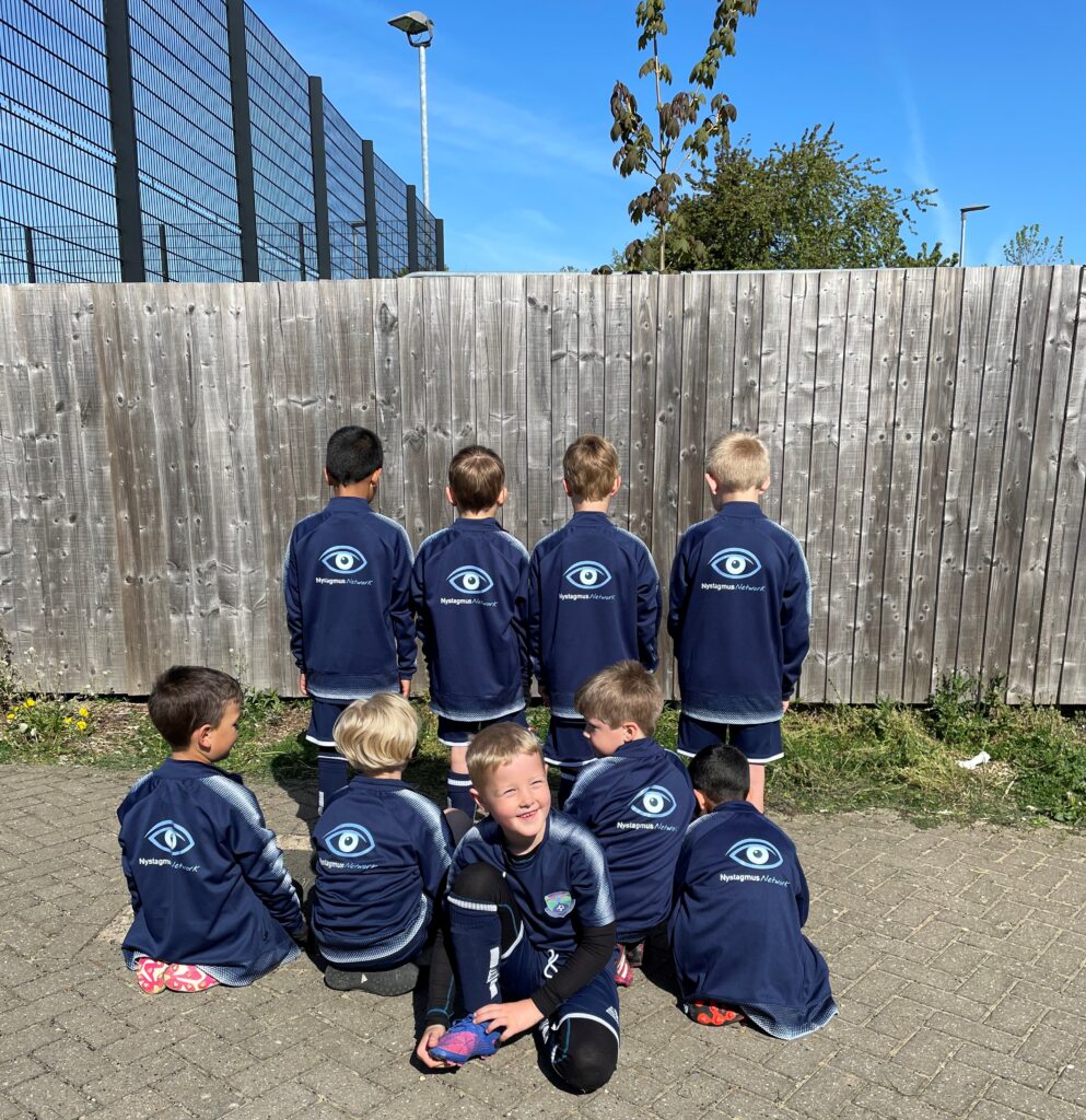 Charlie with members of his football team outside the football club, wearing their Nystagmus Network branded sports tops.