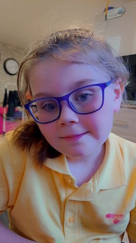 Savannah wears a yellow polo shirt and blue-framed glasses.