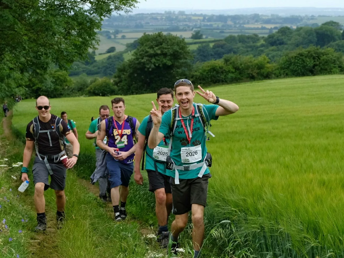 A group of hikers give the thumbs up for the camera with the North Downs countryside in the background.