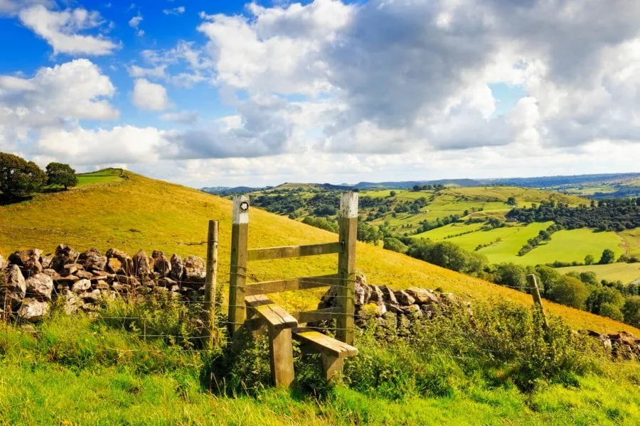 A peak district landscape with a stile in the centre.