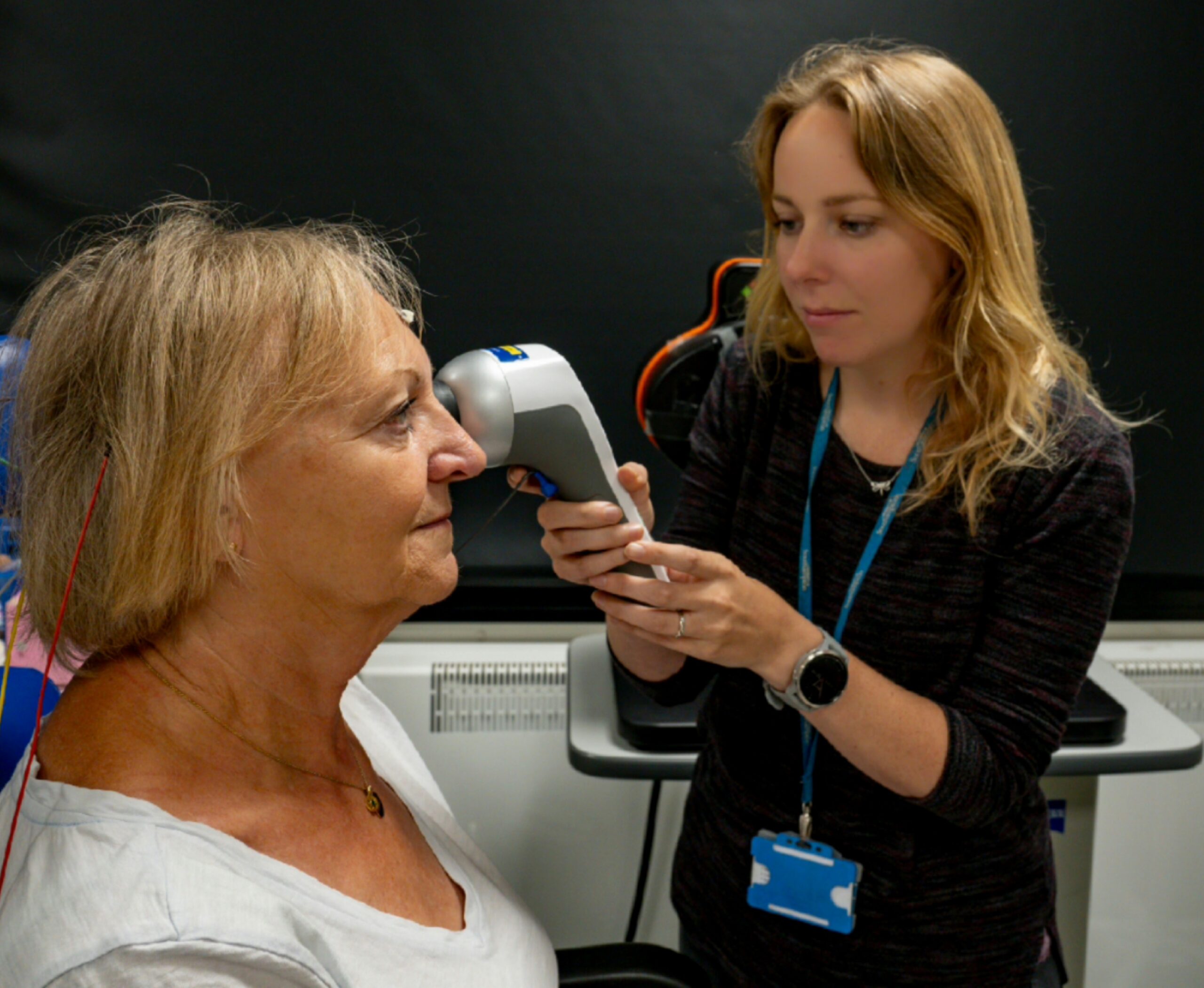 An eye care practitioner is testing a patient's eyes using a RETeval device.