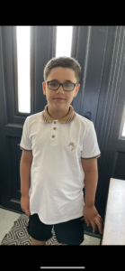 Cohen smiling for the camera, wearing glasses and a white polo shirt with a black striped collar 