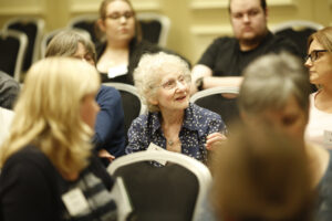 A gropu of people chatting together at a Nystagmus Network event, with the focus on an older lady.