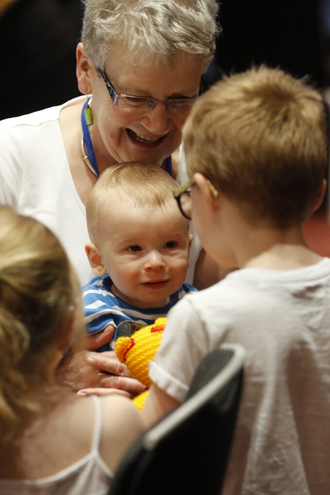 A mature woman interacts with a number of young children.