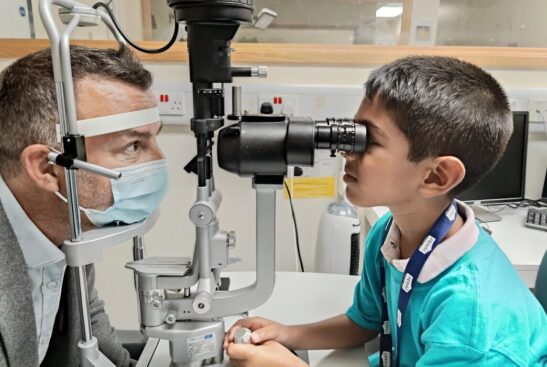 A young child is testing the eyes of an adult.