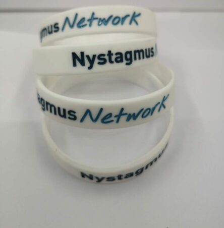 A pile of white children's wristbands with the Nystagmus Network logo.