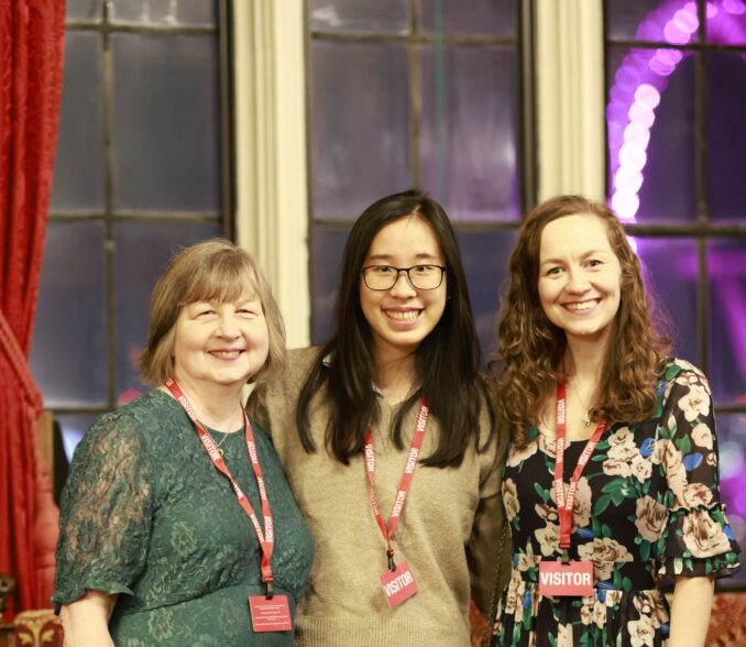 Jackie, Justine and Claire in front of a window showing the London Eye by night.