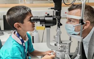 A young child is testing the eyes of an eye doctor using a clinical instrument.