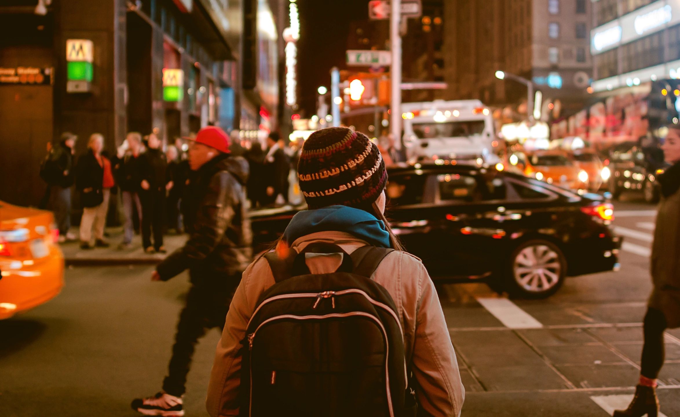 A person carrying a back pack in a very busy street scene.