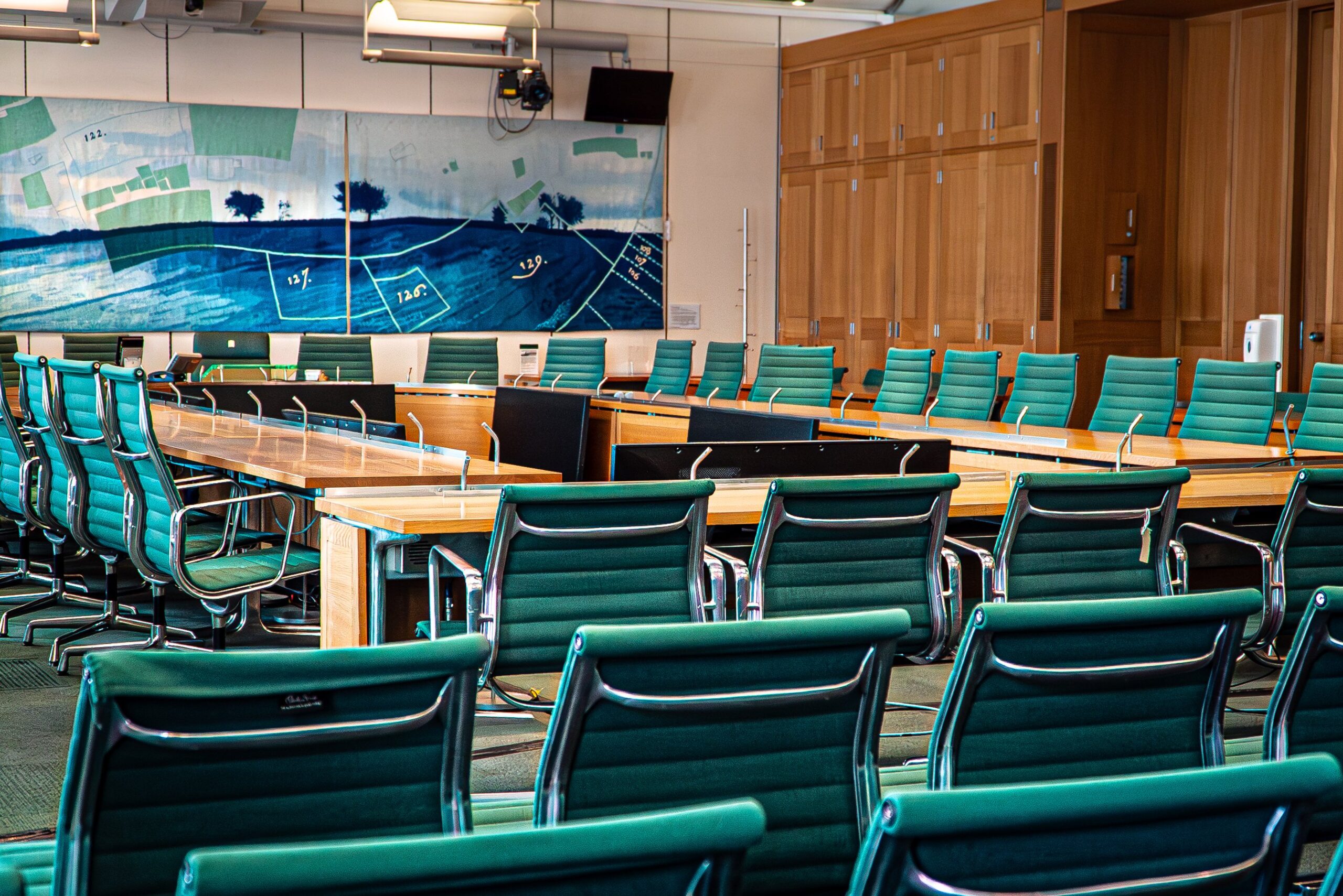 The official image of the SEND inquiry - a classroom or meeting room full of empty desks and chairs.