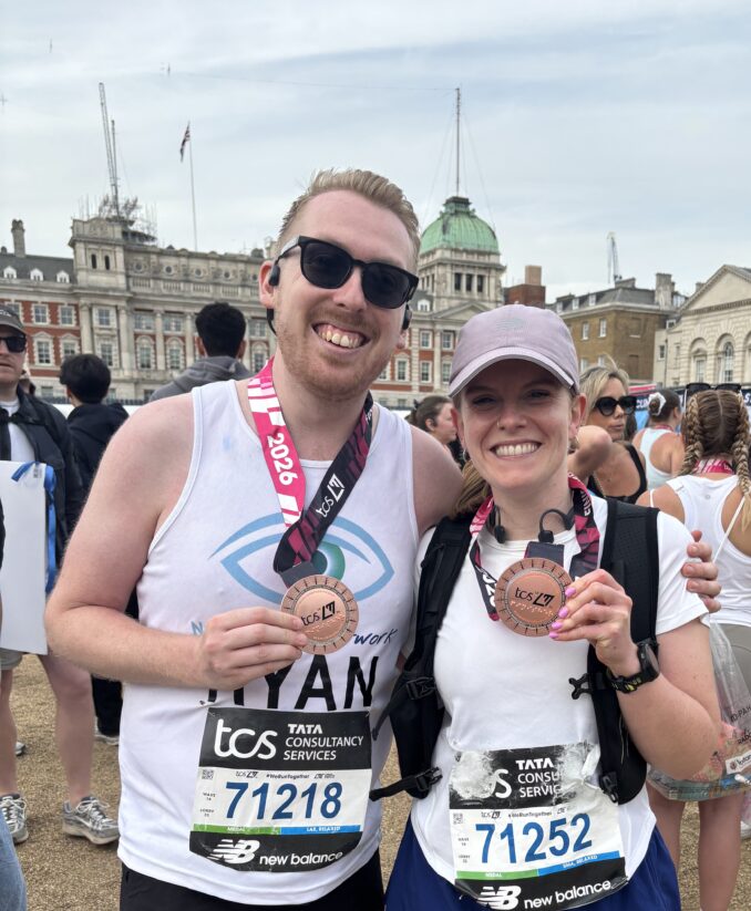 Ryan, wearing his Nystagmus Network running vest and Victoria hold up their finishers' medals.